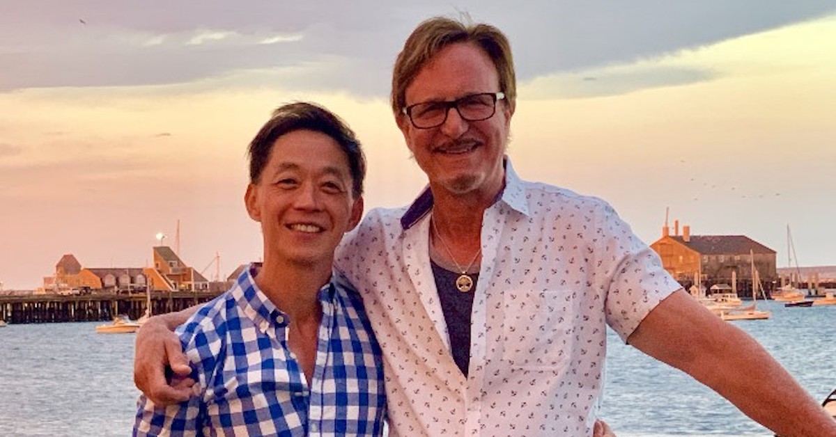 AJ Shepard and Anthony Chiu stand in front of an ocean at sunset