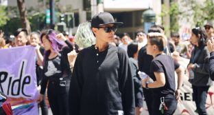 A community safety volunteer stands in front of a crowd of APIENC members marching