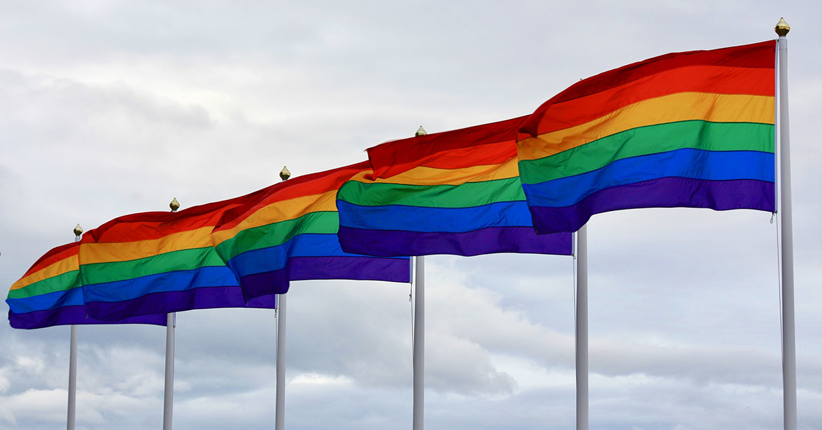 A line of six-striped rainbow flags blowing in the wind