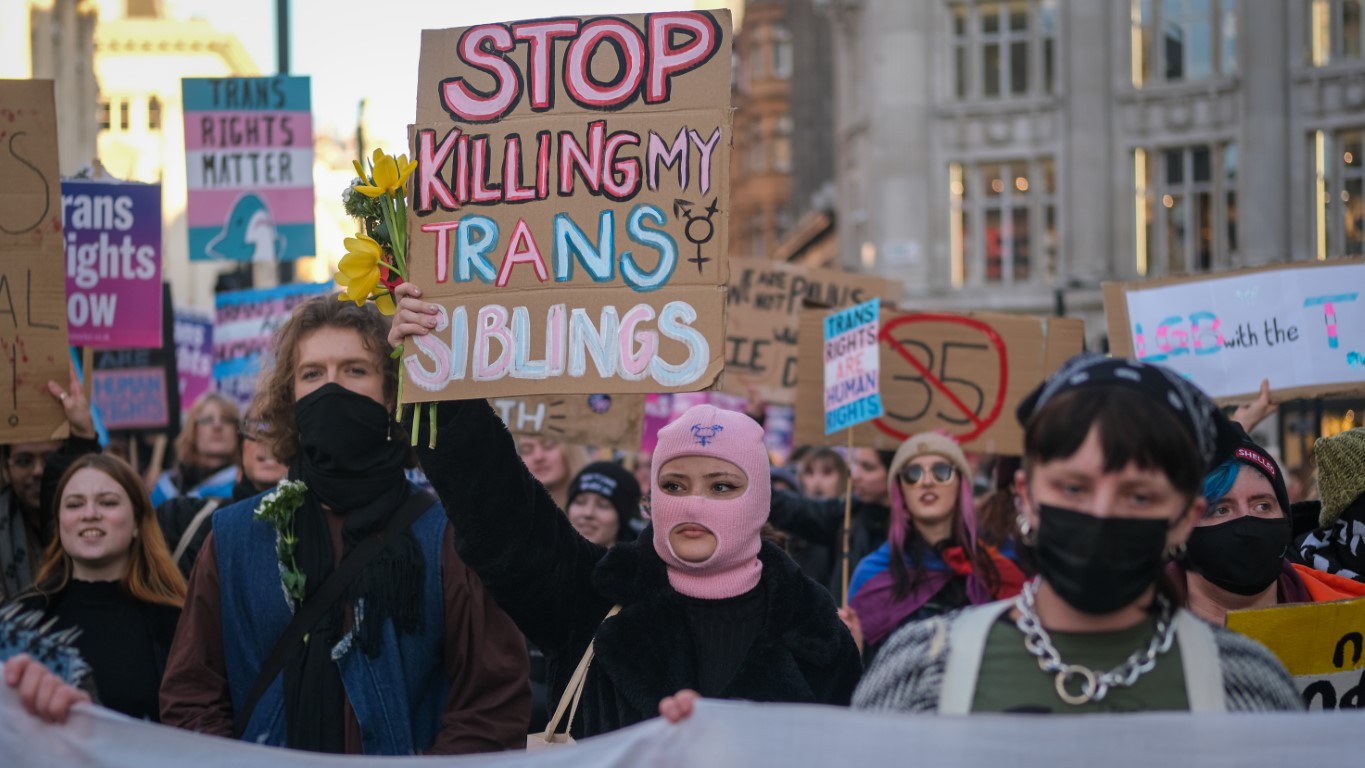 Protestors hold of signs such as "Stop killing my trans siblings" and "LGB with the T"